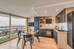 Cozinha moderna com área de jantar, janelas amplas e vista para a cidade.