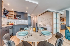 A modern kitchen with a dining area, a bed, and a view of the mountains.