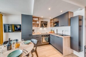 A modern kitchen with dark cabinets, a wooden countertop, and a built-in oven.