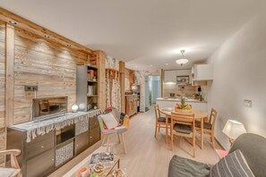 A modern living room with a fireplace, a dining area with a wooden table and chairs, and a kitchen with white cabinets and a microwave. - 300m from resort center, 4th floor, balcony, tv, ski locker, 39m², Tignes (Tignes)