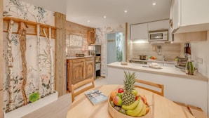 Een moderne keuken met houten kastjes, een centraal eiland en een eethoek met een schaal fruit.
