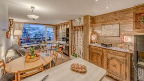 Een gezellige woonkamer met een houten eettafel, stoelen en uitzicht op de stad.
