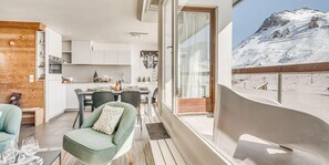 Un intérieur moderne comprenant un coin repas, une cuisine et un balcon avec vue sur la montagne.