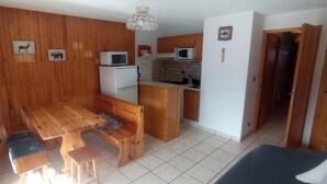 Een kleine keuken met houten kastjes, een magnetron en een koelkast.