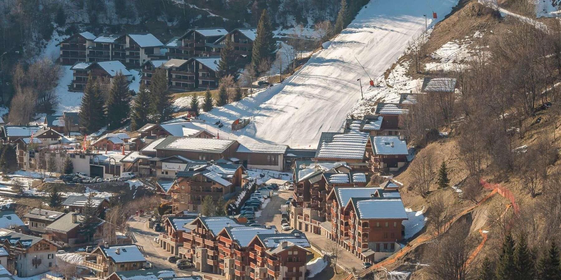A snow-covered mountain town with traditional wooden buildings and a ski slope.