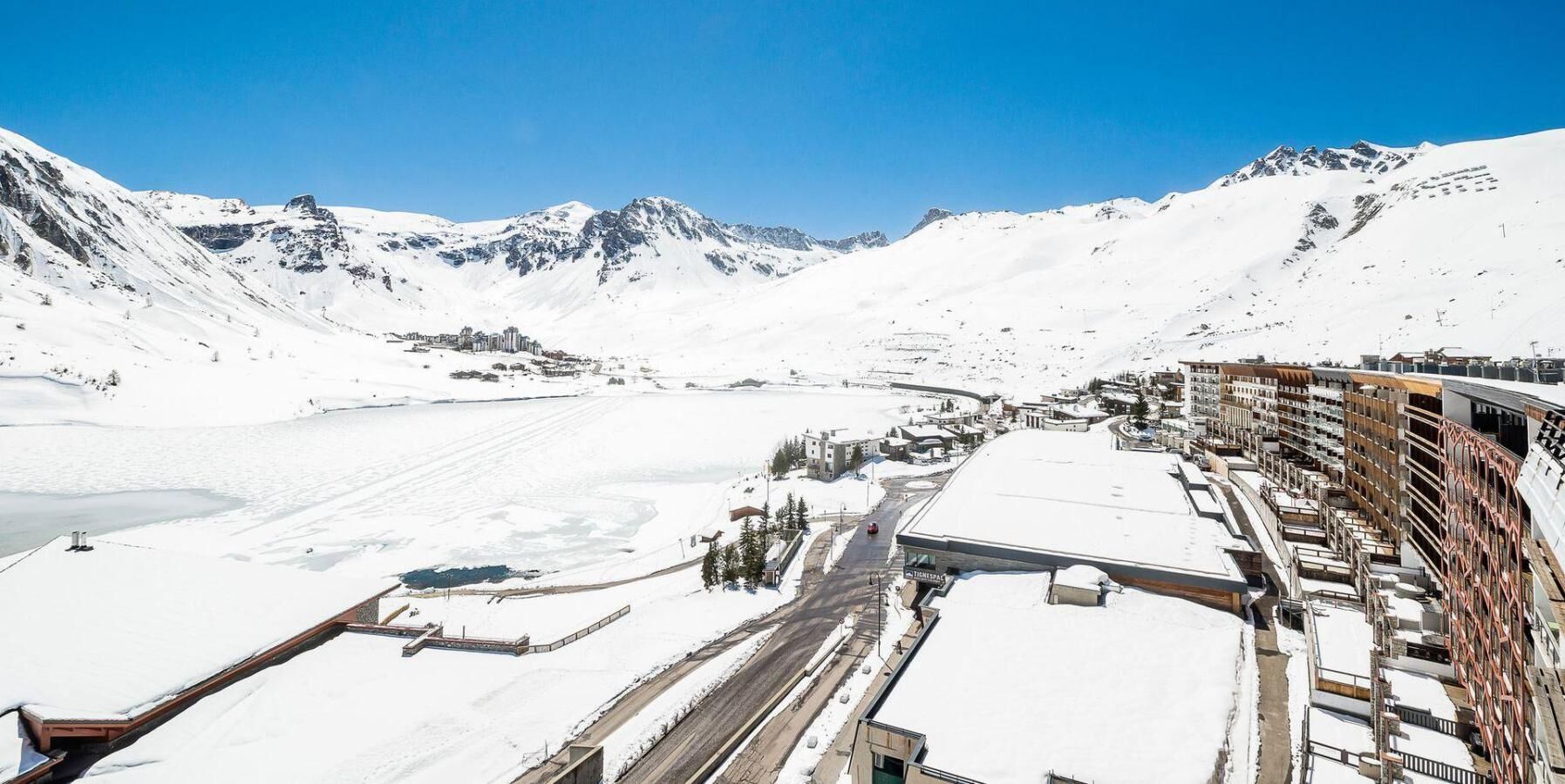 A snow-covered mountainous area with a town and buildings along a road.