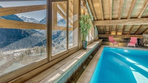 Ein Poolbereich mit Blick auf Berge, Holzbalken und einem Blumentopf.