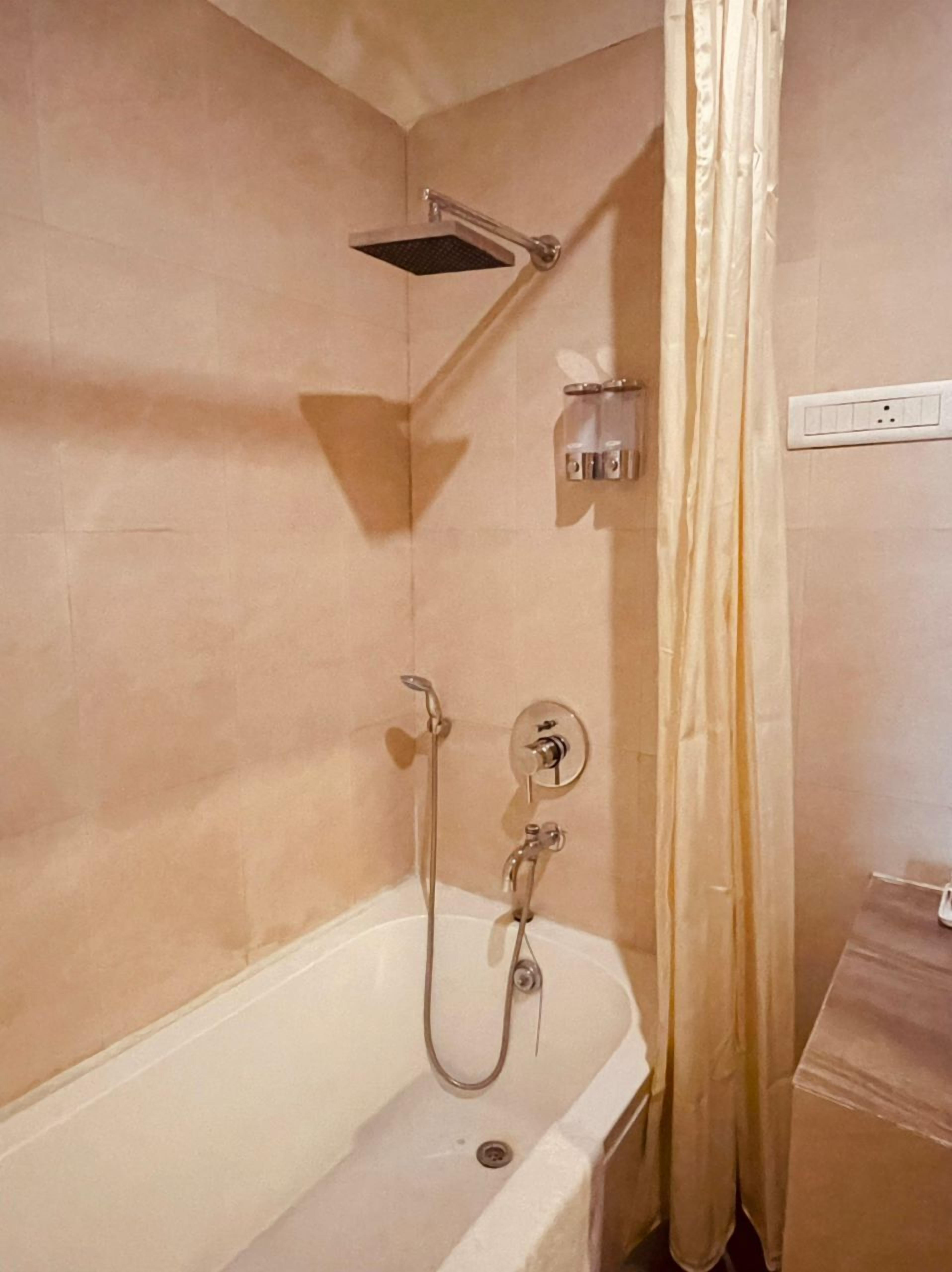 A bathroom with a bathtub, shower, and a towel rack.