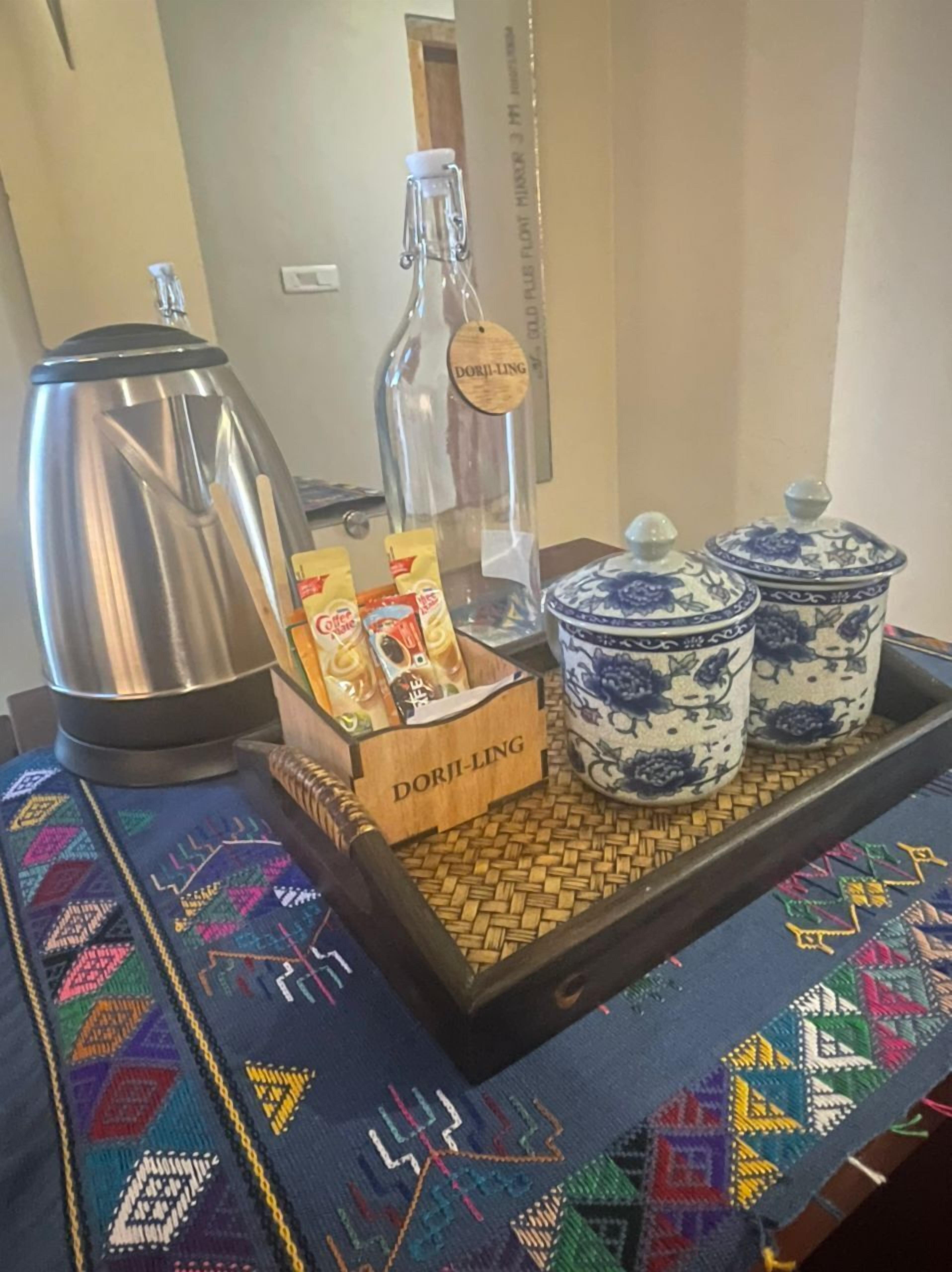 A tray with a coffee pot, a bottle, and containers labeled 'DORJLING' on a table with a patterned tablecloth.