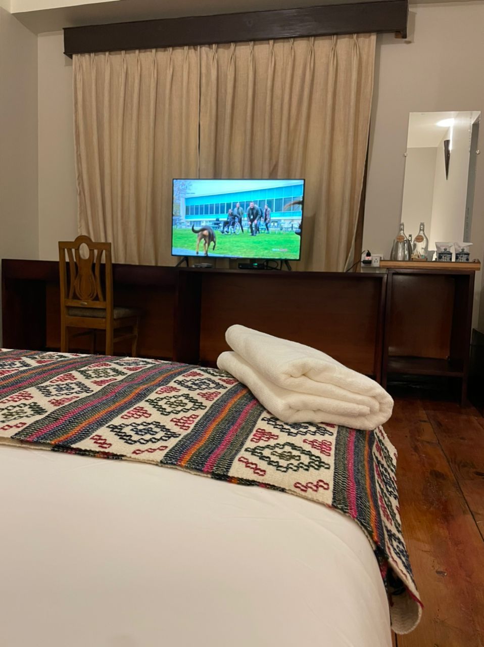 Una camera d'hotel con un letto, una televisione, una scrivania e una sedia.