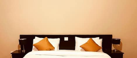 Camera d'hotel con un letto grande, due comodini, un quadro incorniciato al muro e una coperta marrone.