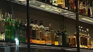 Een bar met meerdere planken vol diverse drankflessen.