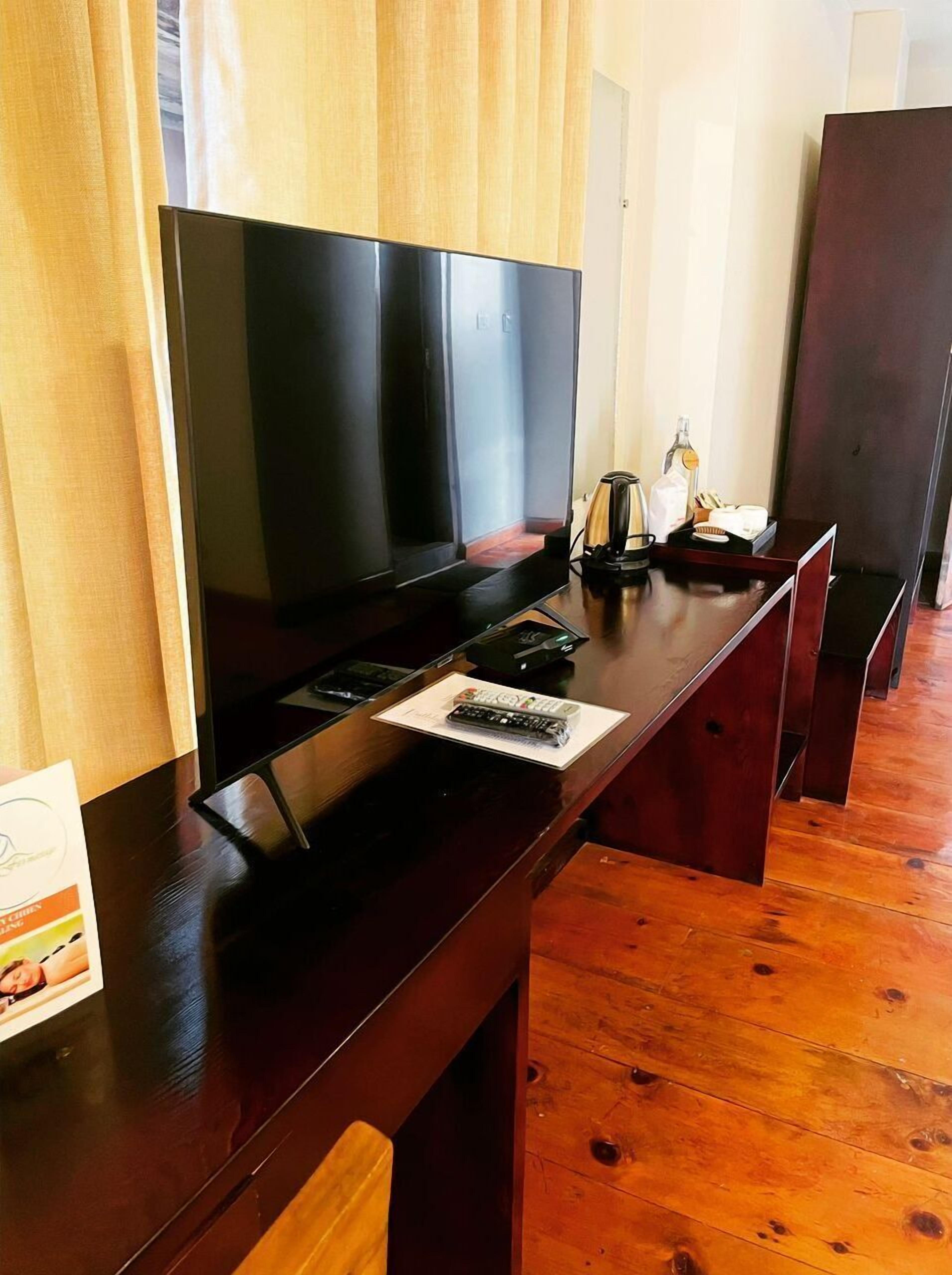 A wooden bar with a flat-screen TV, a remote control, and a menu card.