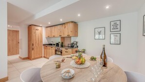 Una cocina moderna con armarios de madera, una mesa de comedor con platos, vasos y un frutero.