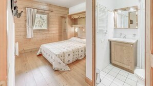Un dormitori amb un llit, una finestra amb cortines i una paret de fusta. La imatge mostra també un bany amb un lavabo, mirall i vàter.