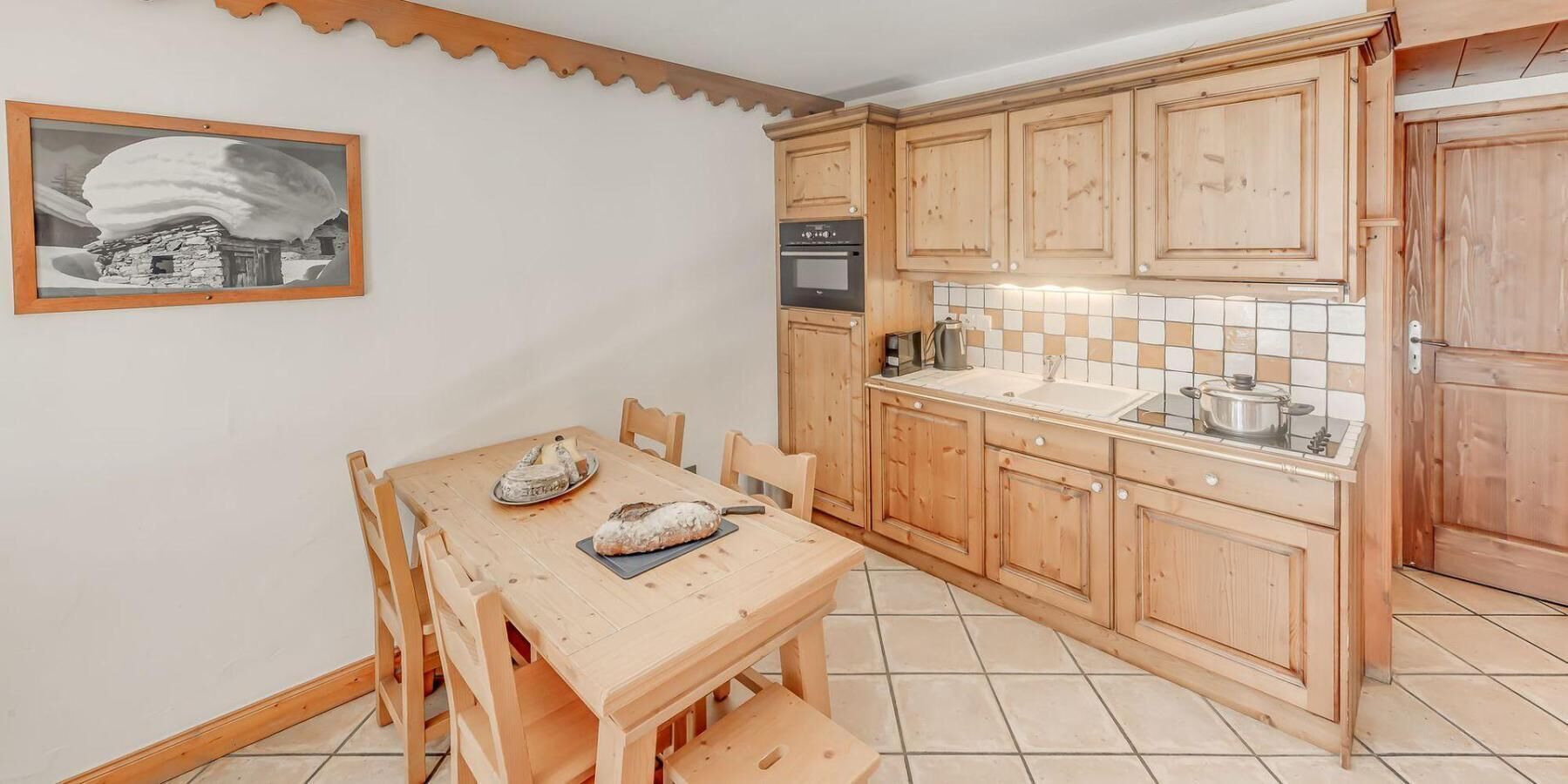 Une cuisine avec des meubles de rangement en bois, un pare-feu en carrelage et une table à manger avec des chaises.
