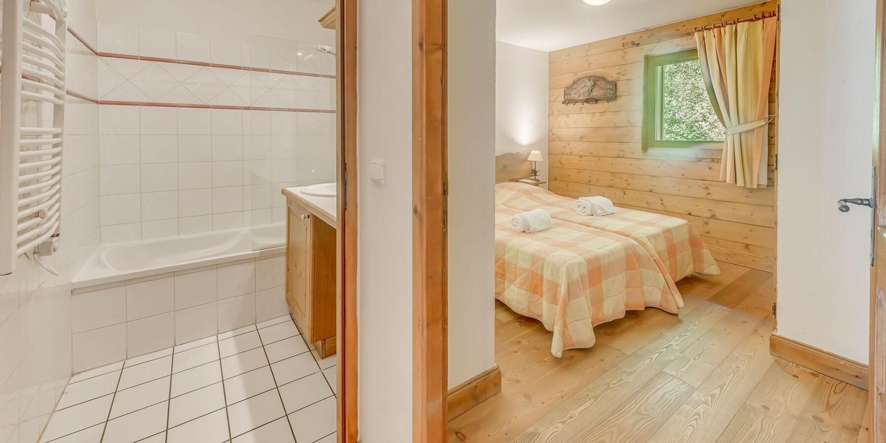 A bathroom with a bathtub and a shower, and a bedroom with two beds and a window.