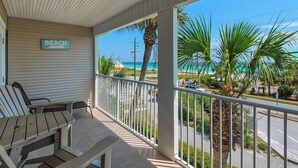 Une véranda abritée avec deux fauteuils de jardin, une pancarte indiquant «PLAGE» et une vue sur l’océan.