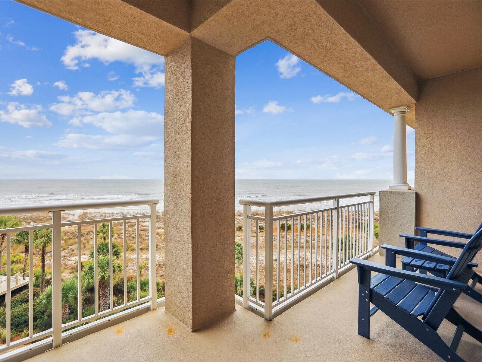 A balcony with a view of the beach and ocean.