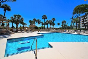 Piscina con sillones de descanso y palmeras.