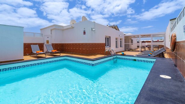 A swimming pool with lounge chairs and a building with a tiled exterior.