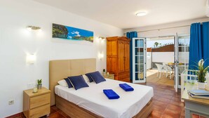 A bedroom with a bed, bedside table, and a view of the balcony.