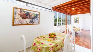 A dining area with a table set for four, a painting on the wall, and a view of the outdoors.