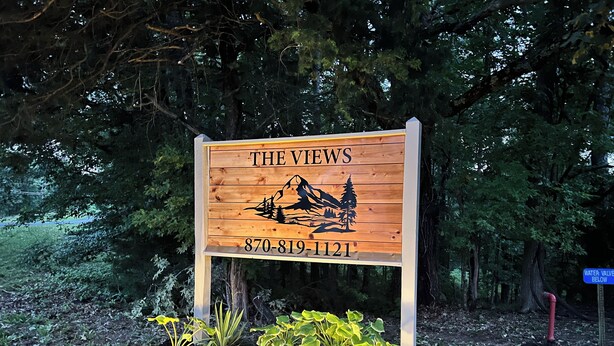 A wooden sign with 'THE VIEWS' and a phone number, surrounded by plants and lights. - Cozy and centrally located in the middle of all the best of nature’s offerings!  (Fifty-Six)