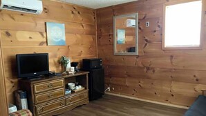 A wooden-paneled room with a television, a dresser, and a mirror. - Cozy and centrally located in the middle of all the best of nature’s offerings!  (Fifty-Six)
