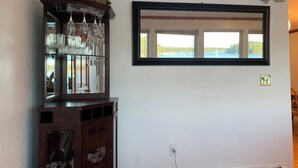A room with a wooden cabinet containing glassware, a mirror, and a window with a view of boats. - Beautiful Oceanfront House- Stunning Water Views (Harpswell)