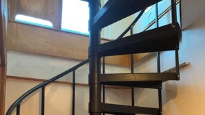A spiral staircase with a metal frame and wooden steps, leading to an upper floor. - Beautiful Oceanfront House- Stunning Water Views (Harpswell)