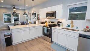 A modern kitchen with white cabinets, stainless steel appliances, and pendant lighting. - Don't Miss Dynamic 4BR/2BA Near Jolly Riverwalk (San Antonio)