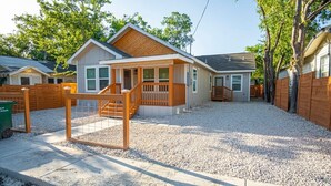 A residential property with a covered porch, a fenced yard, and a gravel driveway. - Don't Miss Dynamic 4BR/2BA Near Jolly Riverwalk (San Antonio)