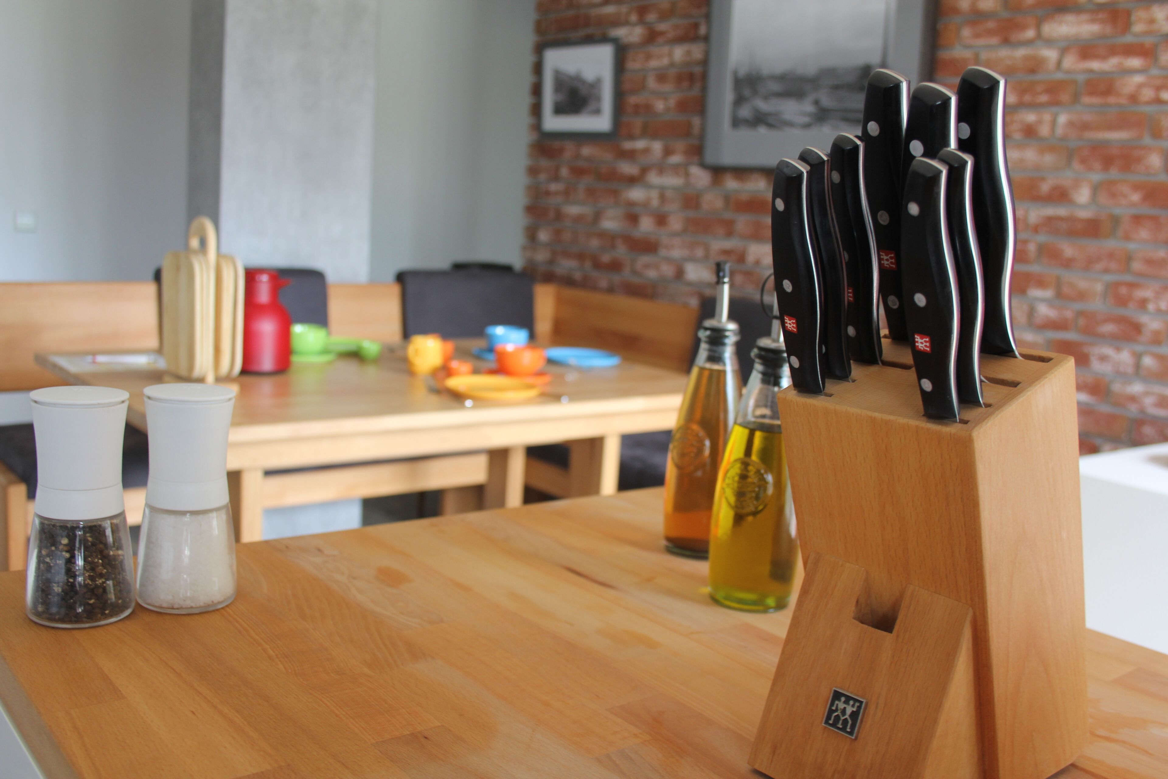 Une cuisine avec une table en bois, des salières et des poivrières, un bloc à couteaux et un mur en briques.