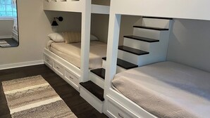 A bunk bed room with a built-in desk and shelving, a bedside lamp, and a window with blinds. - On-site Laundry, ample and secure parking, Fast Wi-Fi, only 10 mi from 1-95 (Savannah)