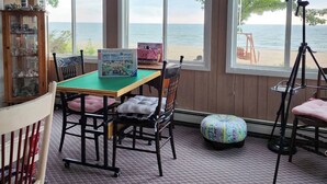 Une pièce confortable avec vue sur la plage, comprenant une table avec des chaises, une bibliothèque et une grande fenêtre.