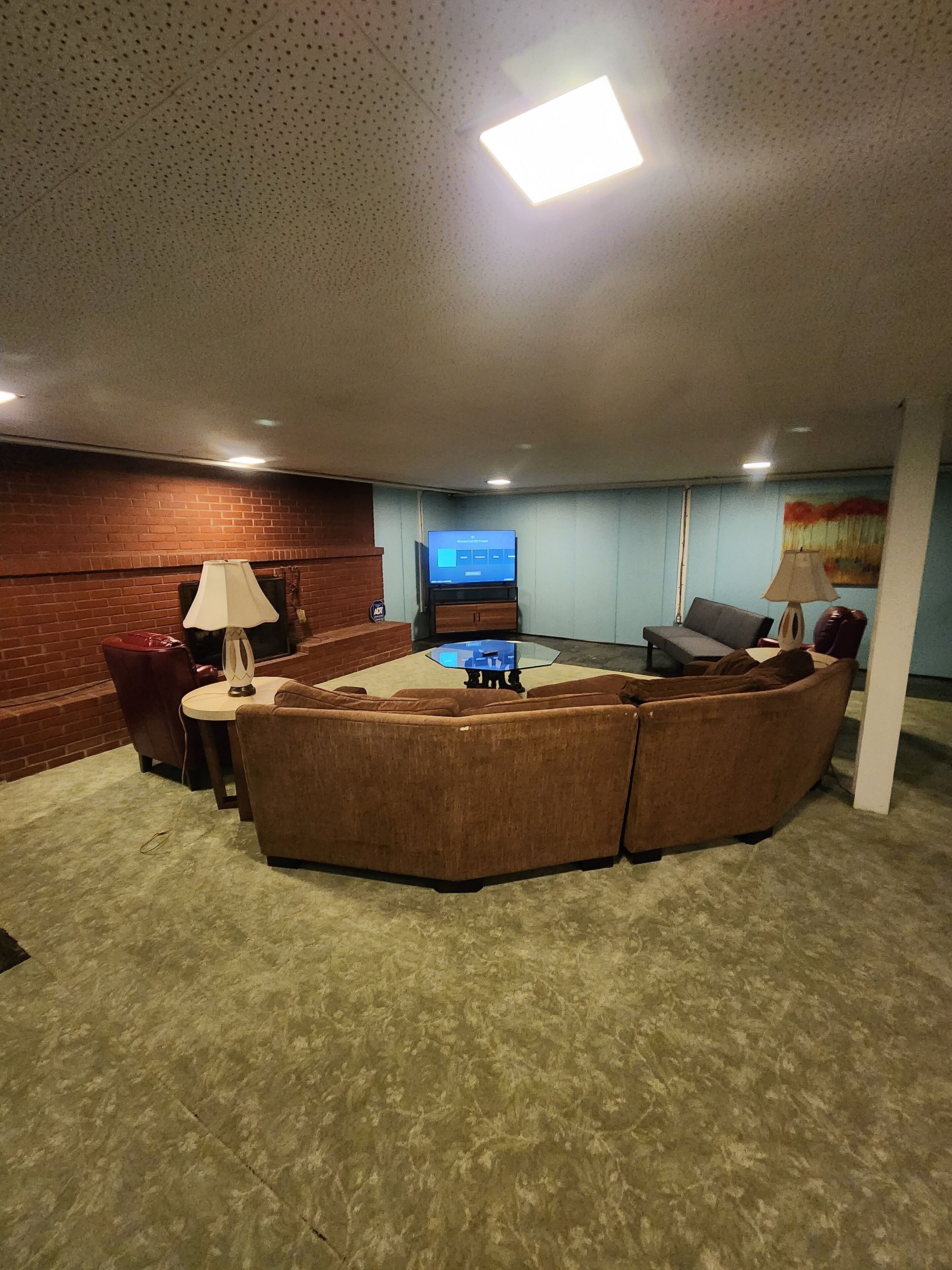 A living room with a sectional sofa, a TV, and a lamp.