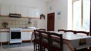 Una cucina con mobili bianchi, un fornello e un tavolo da pranzo con sedie.