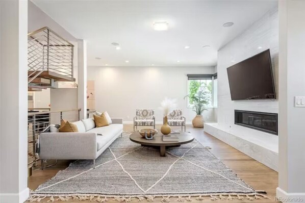 Relax in this inviting living room with a sofa, armchairs, and a flat-screen TV above the fireplace.