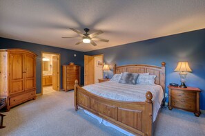 A bedroom with a wooden bed, two nightstands, a ceiling fan, and a wardrobe.