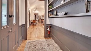A hallway with a patterned rug, a fire extinguisher, and a bookshelf with various items. - The Ashley Suite (Charleston)