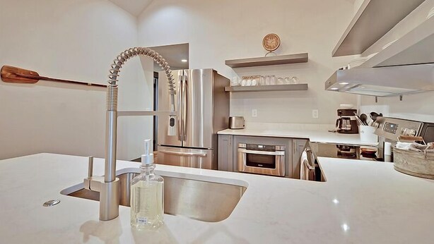 A modern kitchen with stainless steel appliances, a built-in oven, and a unique faucet design. - The Ashley Suite (Charleston)
