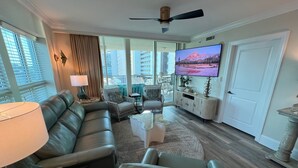Ein modernes Wohnzimmer mit einer Ledersofa, Sesseln, einem Couchtisch und einem flachbildfernseher an der Wand.