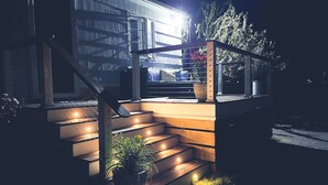 Une maison moderne avec un escalier menant à une terrasse, le tout entouré d’un jardin.