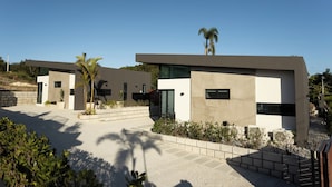 A modern residential complex with multiple houses featuring flat roofs, large windows, and a minimalist design. - Luxury Villa with private pool, Steps away from Black Eagle Beach (Rincón)