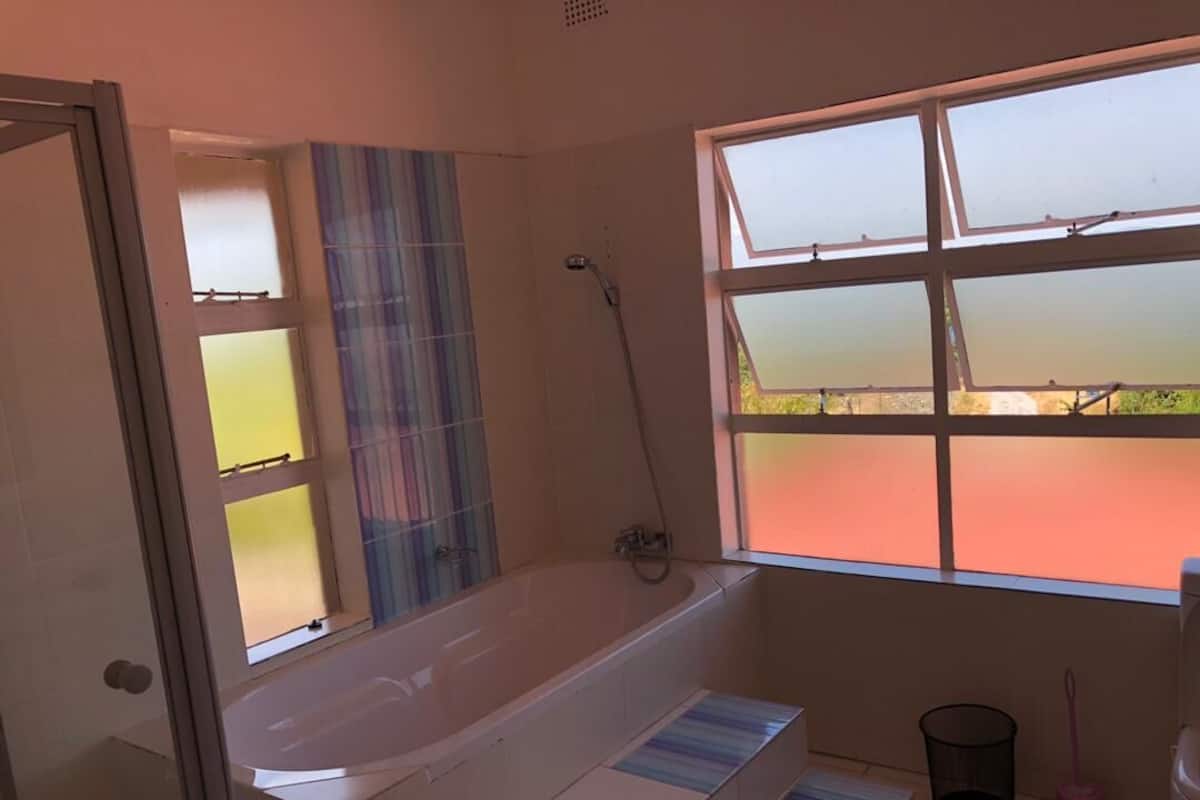 Une salle de bain avec une baignoire, une fenêtre donnant sur un beau paysage et une douche.