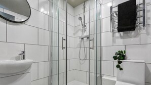 Une salle de bain moderne avec une douche à parois de verre, un lavabo blanc et des toilettes.
