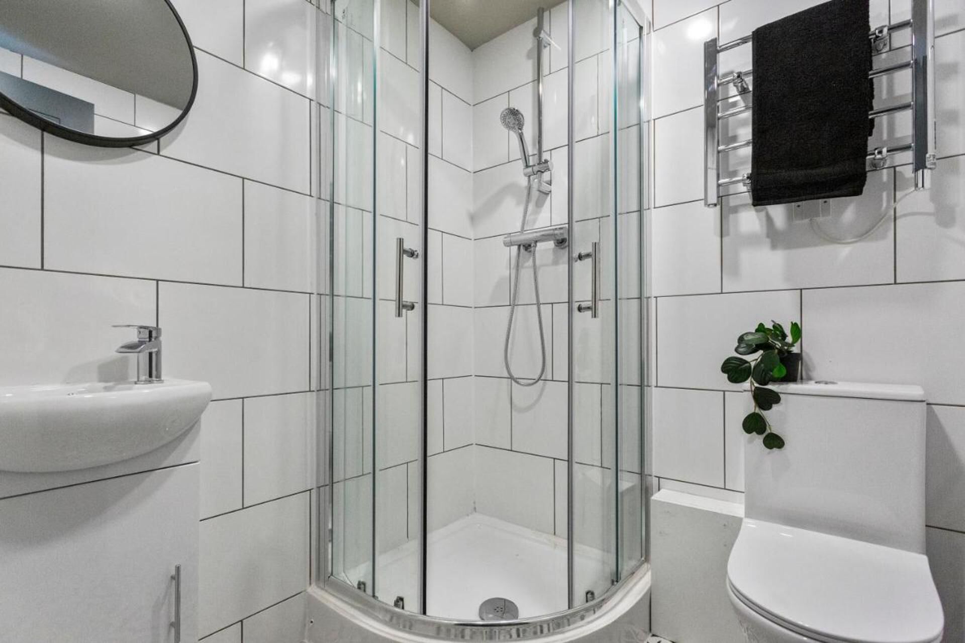 Un baño moderno con cabina de ducha de vidrio, lavabo blanco y retrete.