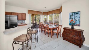 A spacious kitchen with a dining area, wooden cabinets, and a large window.