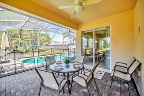 A covered patio with a pool, outdoor seating, and a ceiling fan. - Near Disney Amazing 5 Bd Home - Private Pool (Davenport)